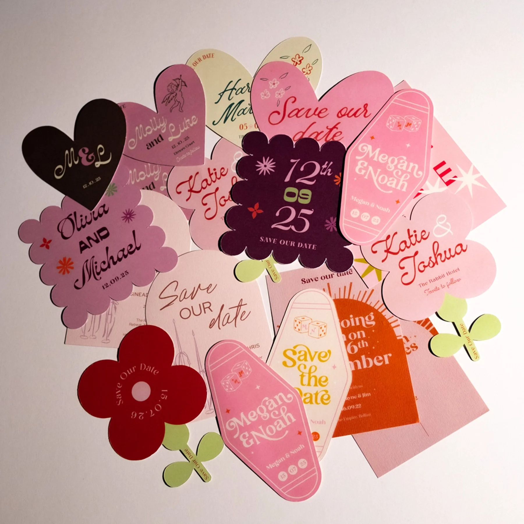 Collection of colorful paper wedding save-the-date cards and stickers with various designs, names, and dates.