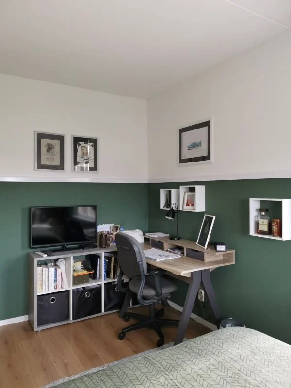 En-Casa combineerde in de slaap- en studeerkamer een werkplek met een compacte tv-hoek, zodat de ruimte meerdere functies krijgt zonder druk te worden. De groene lambrisering geeft een stoere basis en het wit bovenin houdt het geheel licht. Met geslo