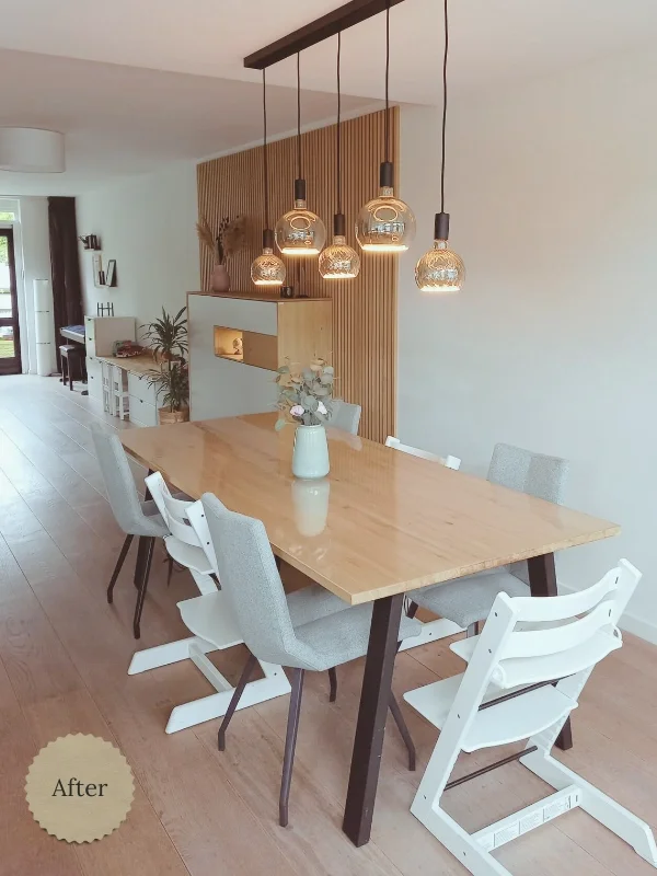 Deze foto toont de vernieuwde eetkamer uit het project woonkamer & eetkamer make-over in Aalsmeer. De lichte houten eettafel, zachte stoelen en warme hanglampen creëren een rustige en uitnodigende sfeer, terwijl de houten lattenwand zorgt voor extra 