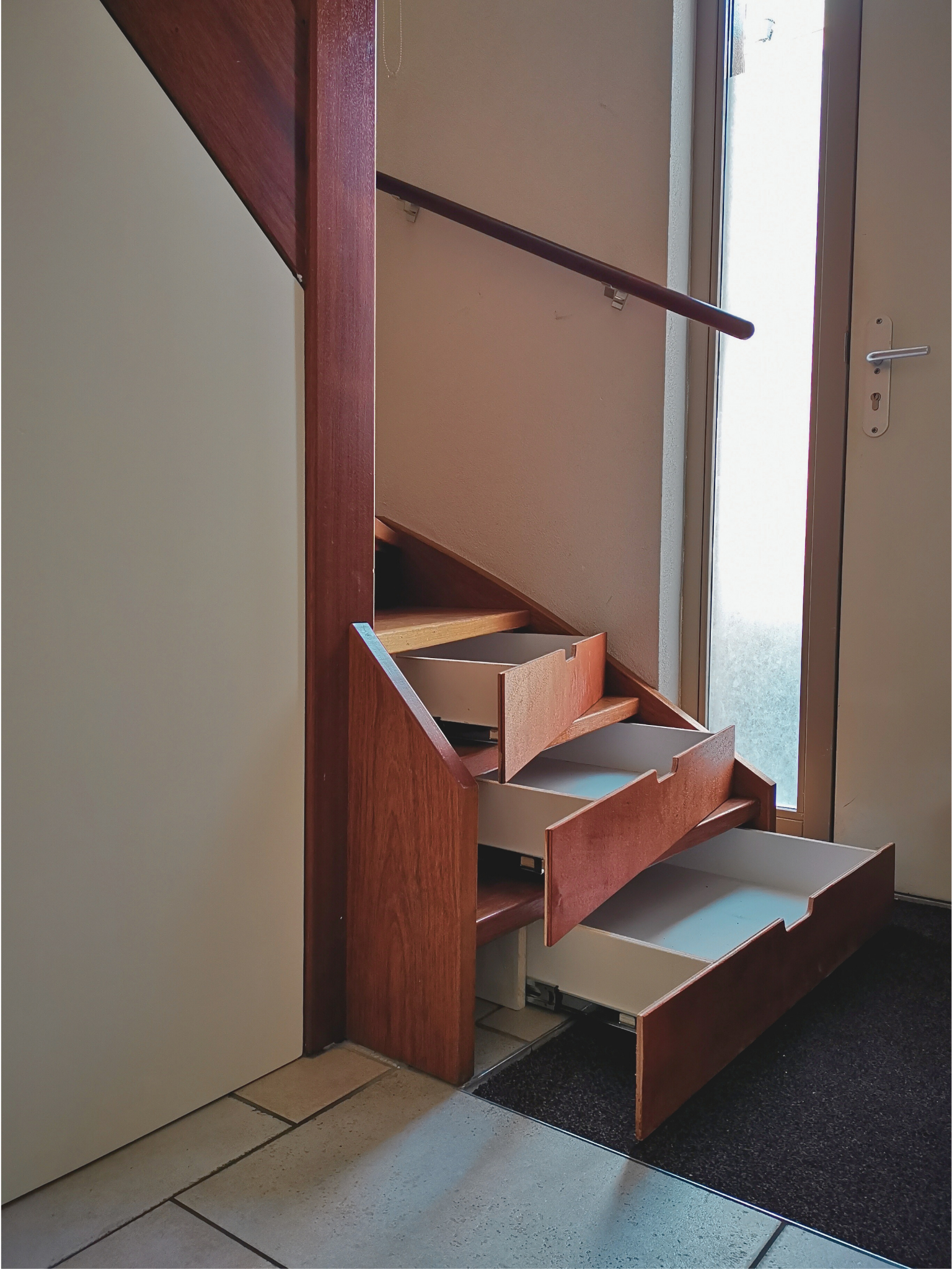 Maatwerk trap met geïntegreerde opberglades voor extra bergruimte in de entree. Slim ontwerp dat functionaliteit en stijl perfect combineert.