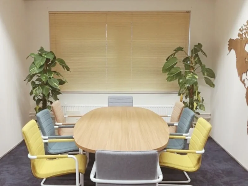 Kantoorverbouwing Select Uitzendbureau (Uitgeest): vernieuwde vergaderruimte met houten tafel, kleurstoelen en planten. Ontwerp en styling door En-Casa
