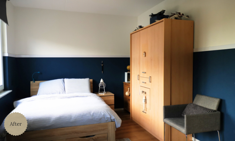 Een rustige, lichte slaapkamer met een diepblauwe accentwand die meteen sfeer geeft. Het houten bed en de grote houten kast zorgen voor warmte en een natuurlijke basis. Door het lichte beddengoed blijft de ruimte fris en open, met een fijne balans tu