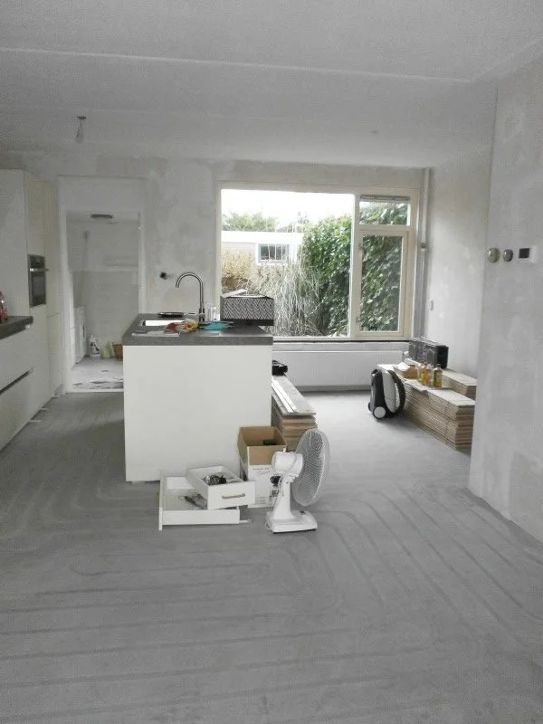 Deze foto toont de voor-situatie van de woonkamer & eetkamer: een open, lichte ruimte waarin alleen de keuken aanwezig is. De neutrale afwerking en de lege woonkamer maken de indeling en de mogelijkheden voor de make-over goed zichtbaar.