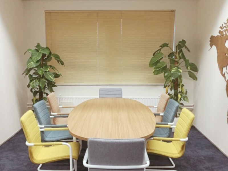 Kantoorverbouwing Select Uitzendbureau (Uitgeest): vernieuwde vergaderruimte met houten tafel, kleurstoelen en planten. Ontwerp en styling door En-Casa.