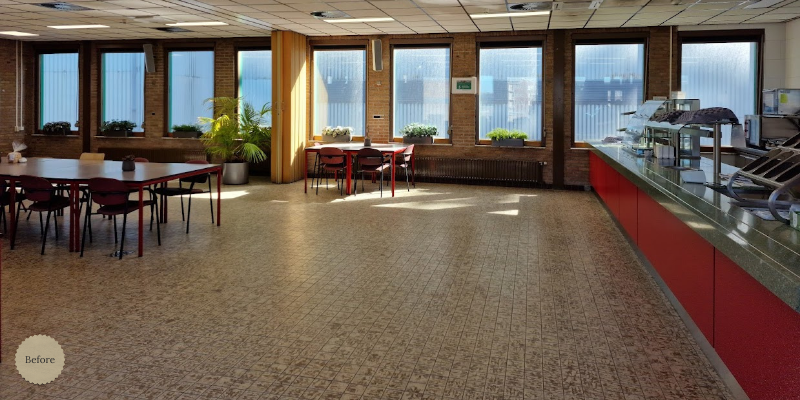 Ruime, lichte bedrijfsrestaurant- of kantineruimte met grote raampartijen, rode toonbank en flexibele zitopstelling—ideaal als inspiratie voor een functionele, uitnodigende lunchplek voor medewerkers en bezoekers.