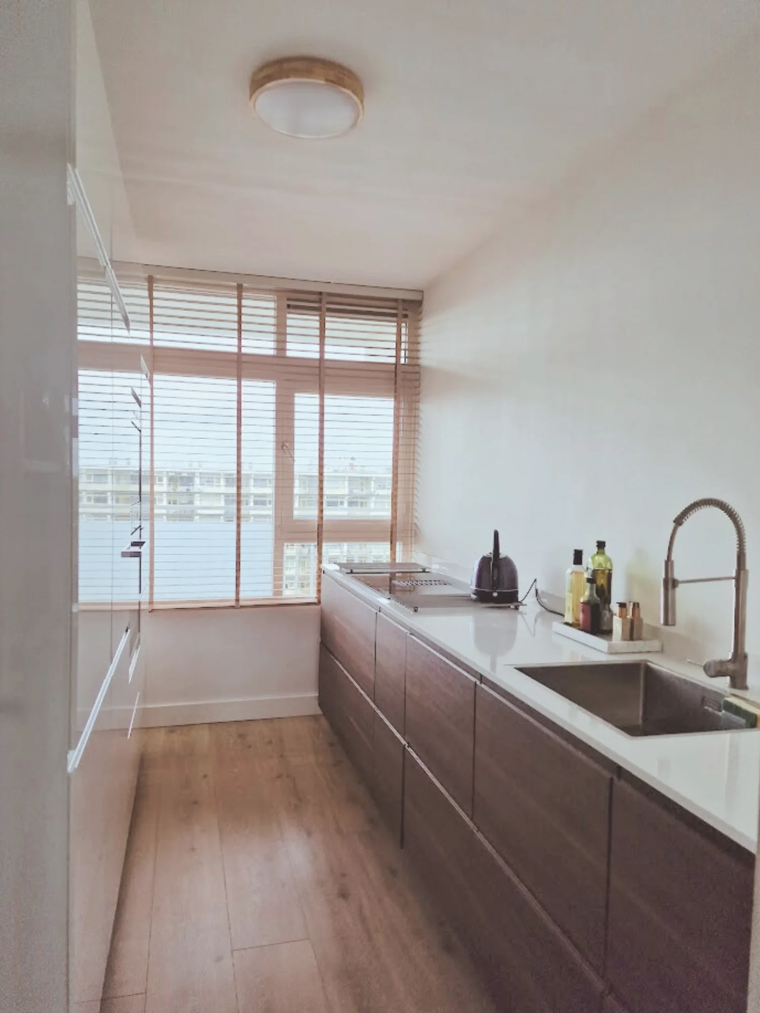 Keuken met kastenwand én één lange werkruimte: veel opbergruimte aan één zijde en een strak, rustig werkblad aan de andere kant.  Interieuradvies, interieurontwerp en styling door En-Casa Interiors in Noord-Holland.
