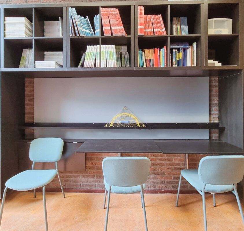 Moderne kantoorinrichting met flexibele werkplek, maatwerk kastenwand, comfortabele stoelen en een slimme klaptafel voor laptops, perfect voor kort overleg of geconcentreerd werken.