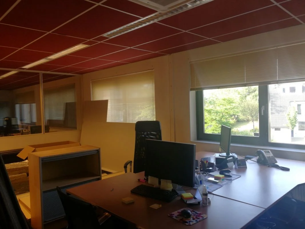  kantoorinrichting vóór herinrichting en interieurontwerp. Bestaande werkplekken met bureaus, schermen en daglicht.