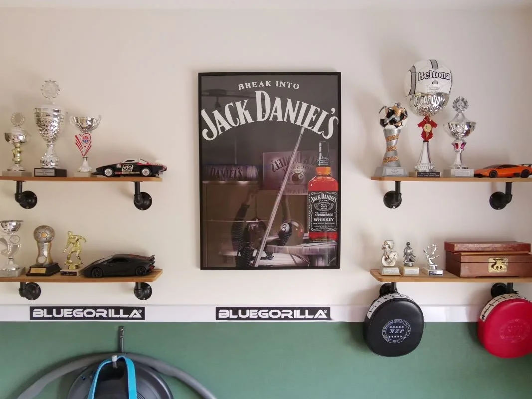 Deze wand maakt de kamer echt eigen. En-Casa bundelde alle herinneringen van de jonge man op industriële planken, strak geordend en mooi in beeld. Zo blijft de ruimte rustig, maar krijgt hij wel een persoonlijk verhaal.