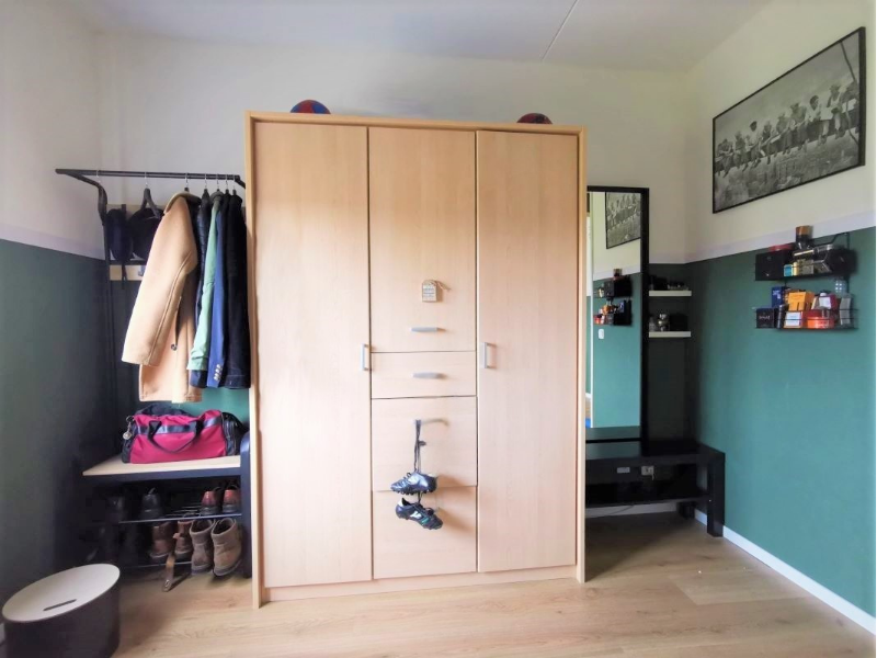 In de tweede kamer creëerde En-Casa een walk-in closet gevoel met een slimme combinatie van een dichte kast, een kledingrek en een wandspiegel. Zo ontstaat een duidelijke plek om kleding te hangen, te kiezen en aan te kleden, zonder dat de ruimte vol