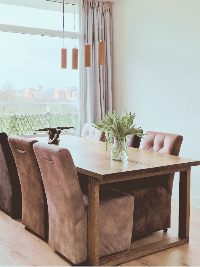 Gezellige eetkamer met warme houttinten, zachte stoelen en hanglampen. Een praktische, rustige plek om samen te eten en te genieten.