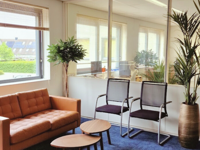 Kantoorverbouwing Select Uitzendbureau (Uitgeest): vernieuwde wachtruimte met warme zitbank, houten tafeltjes en groenaccenten. Ontwerp en styling door En-Casa.