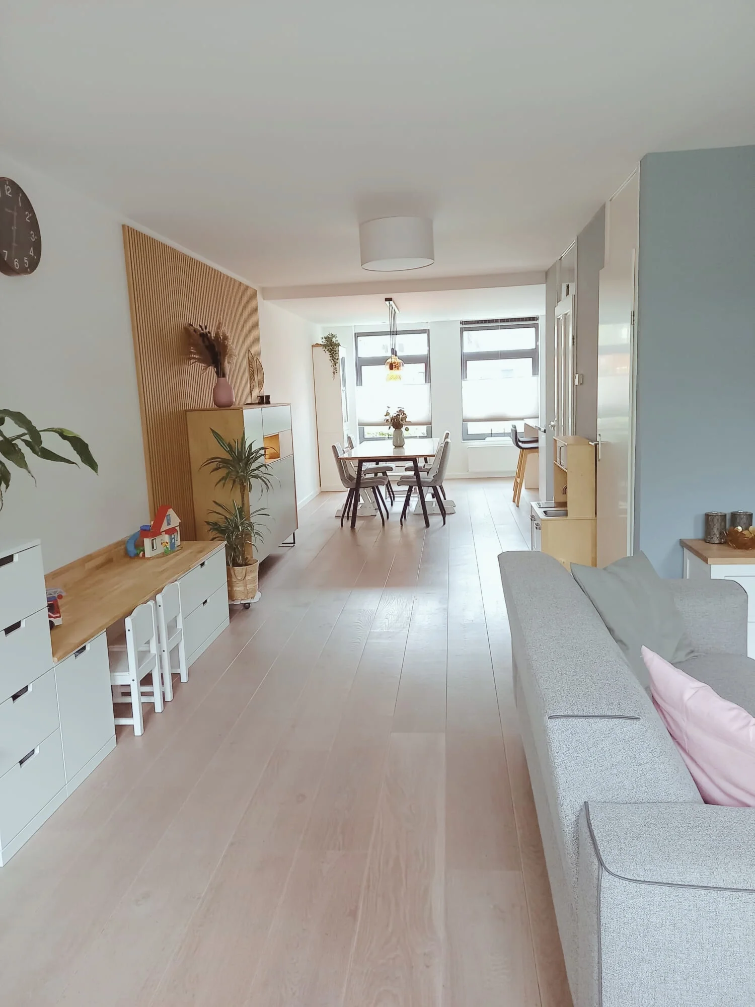 Woonkamer met open zichtlijn naar de eethoek, een rustige basis in zachte tinten en warm hout. Scandinavisch-modern interieur met veel daglicht en een fijne flow tussen wonen en eten — een en casa dat klopt.  Interieuradvies, interieurontwerp en styl