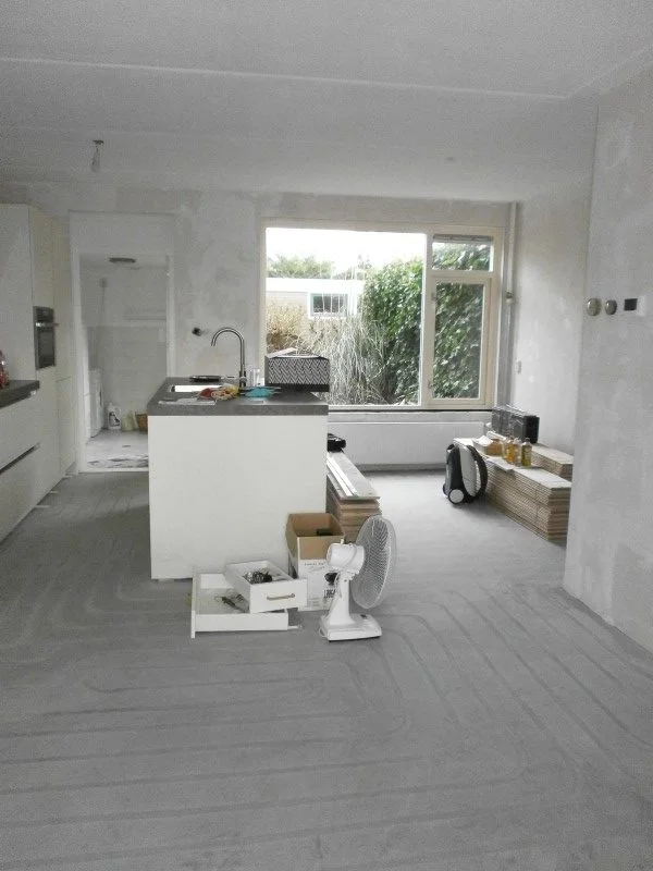 Deze foto toont de voor-situatie van de woonkamer & eetkamer: een open, lichte ruimte waarin alleen de keuken aanwezig is. De neutrale afwerking en de lege woonkamer maken de indeling en de mogelijkheden voor de make-over goed zichtbaar.