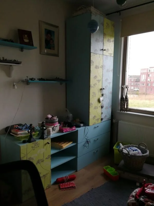 Before: bestaande situatie van de kinderkamer met opbergkast en open vakken bij het raam. Functioneel, maar visueel onrustig. En-Casa vertaalde dit later naar een rustig en volwassen totaalbeeld.