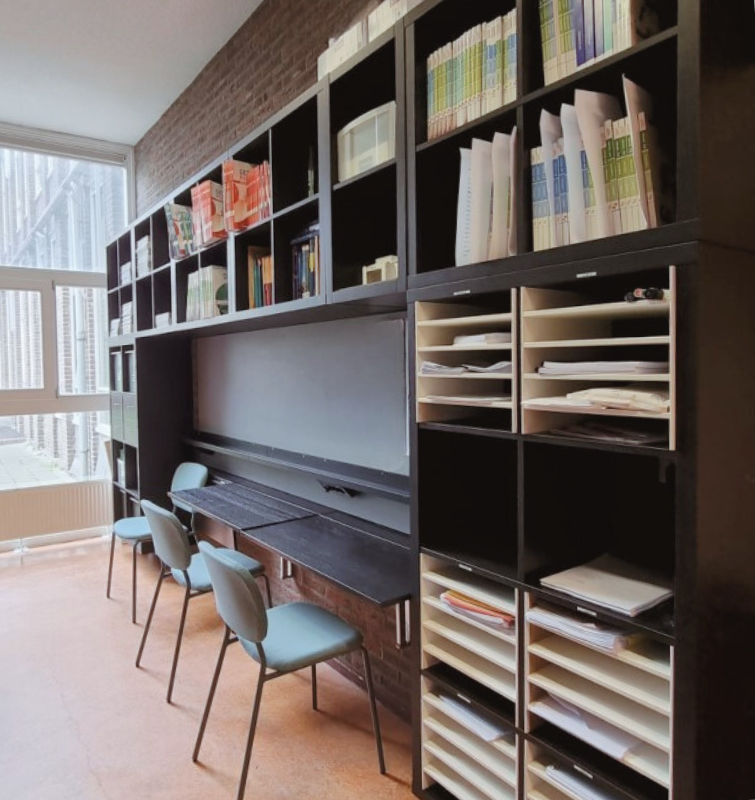 Moderne kantoorinrichting met maatwerk kastenwand, royale opbergruimte voor dossiers en papierwerk, extra zitplekken en veel daglicht voor een rustige, georganiseerde werkruimte.