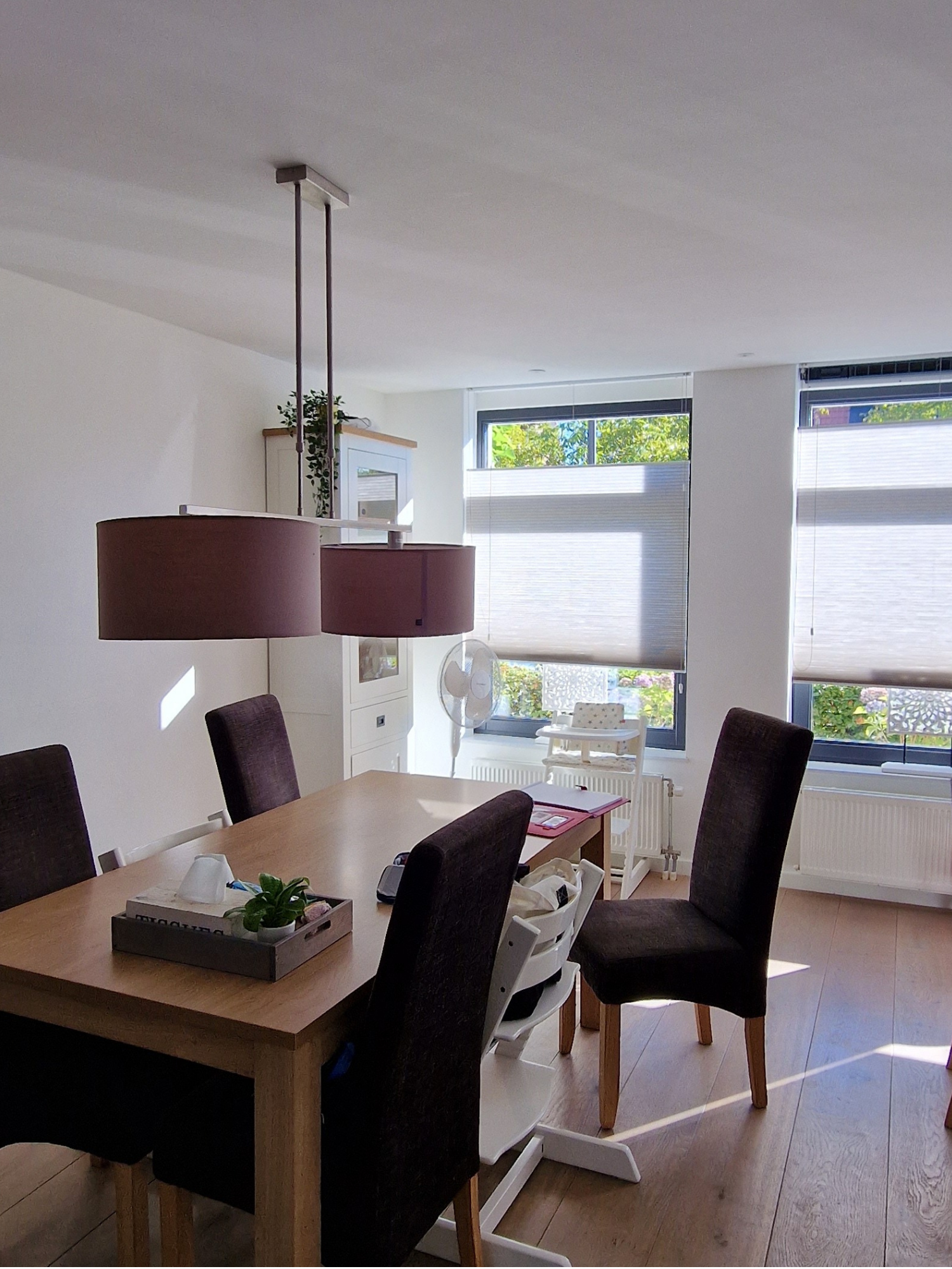 “Voorfoto van een lichte, rustige woonkamer met grijze hoekbank, witte salontafel en tv-meubel op een warme houtlook vloer.”