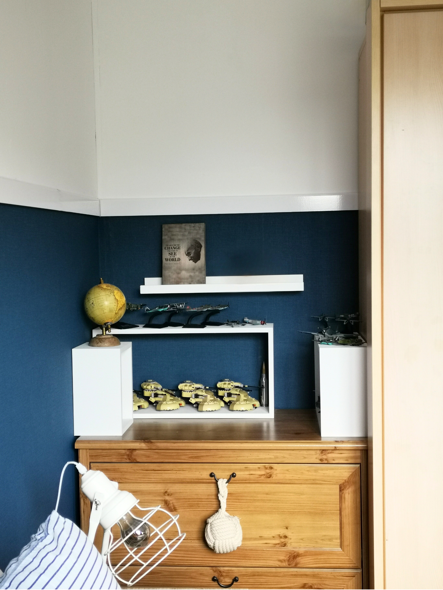 Een sfeervol hoekje in de slaapkamer waar kleur, hout en styling mooi samenkomen. De diepblauwe accentwand geeft rust en diepte, terwijl het houten dressoir zorgt voor warmte en een natuurlijke basis. Met een paar persoonlijke accessoires, zoals een 