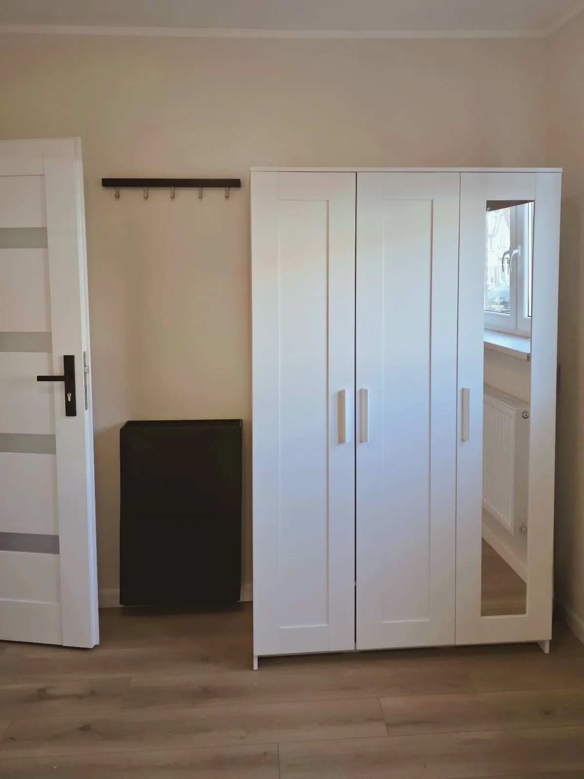 Een strakke, witte kledingkast met spiegeldeur en wandhaken — slimme opbergruimte die de kamer licht en rustig houdt, zodat jij ’s ochtends zonder zoekactie (of stress) je dag start en je meteen en casa voelt.