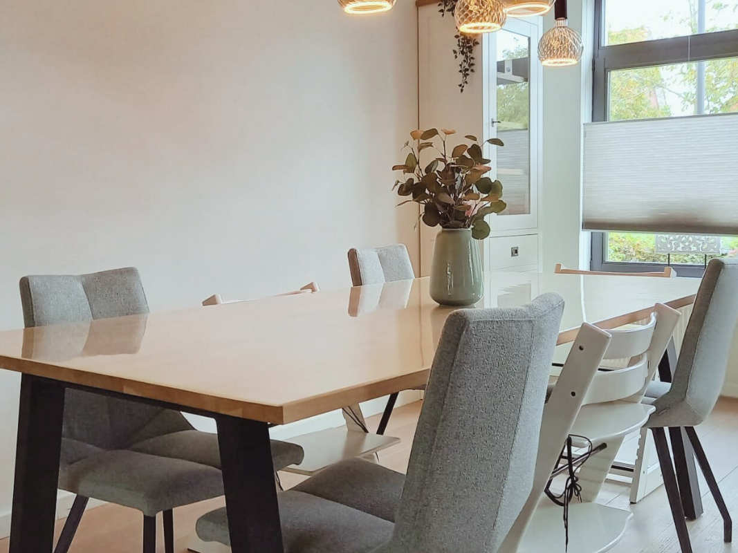 SEO description / alt-tekst:
Lichte moderne eethoek met houten eettafel, zachte stoffen stoelen en natuurlijke tinten. Een rustige, warme eetkamer met veel daglicht, passend bij een en casa interieur waar comfort en sfeer samenkomen.