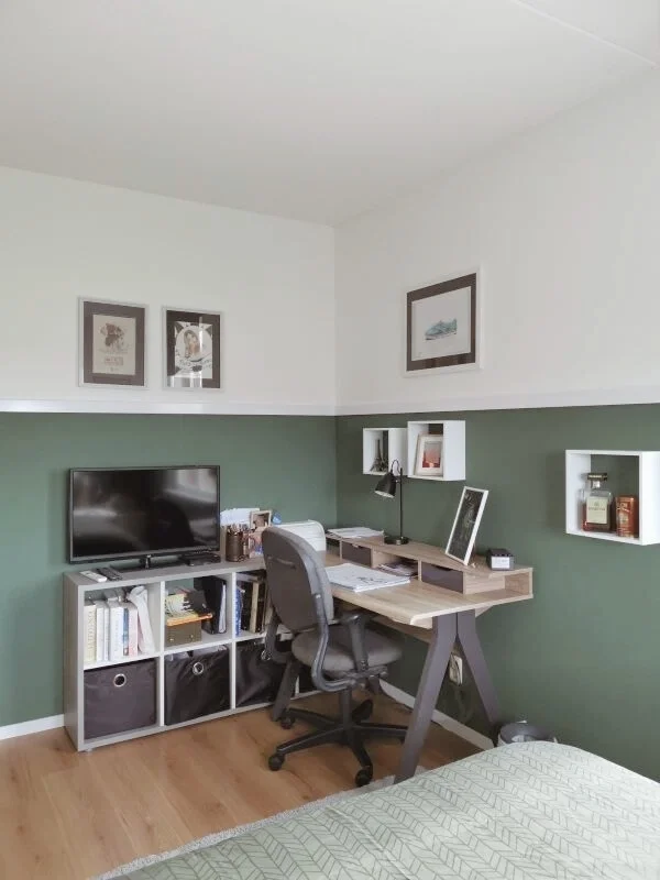 En-Casa combineerde in de slaap- en studeerkamer een werkplek met een compacte tv-hoek, zodat de ruimte meerdere functies krijgt zonder druk te worden. De groene lambrisering geeft een stoere basis en het wit bovenin houdt het geheel licht. Met geslo