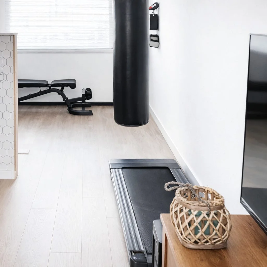 Rustige garage gym hoek met bokszak en lichte vloerafwerking, strak en praktisch gestyled voor dagelijks trainen – En-Casa interieuradvies en styling in Heemskerk.