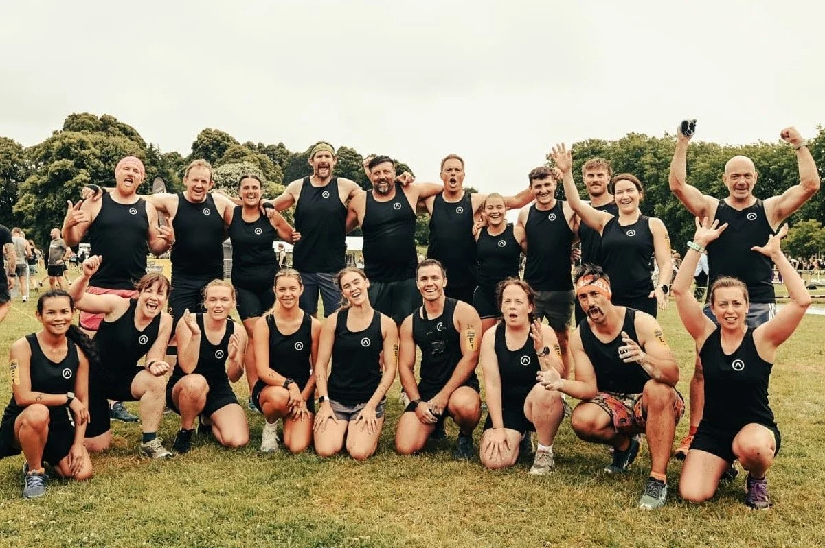 A group of people in black athletic gear posing together outdoors, celebrating after a sporting event, with trees in the background.