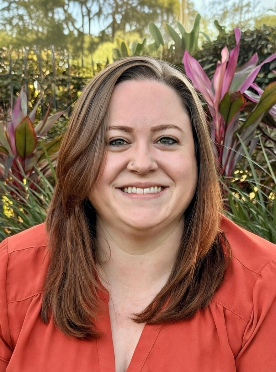 Therapist Samantha Savage smiling outdoors, wearing a coral top
