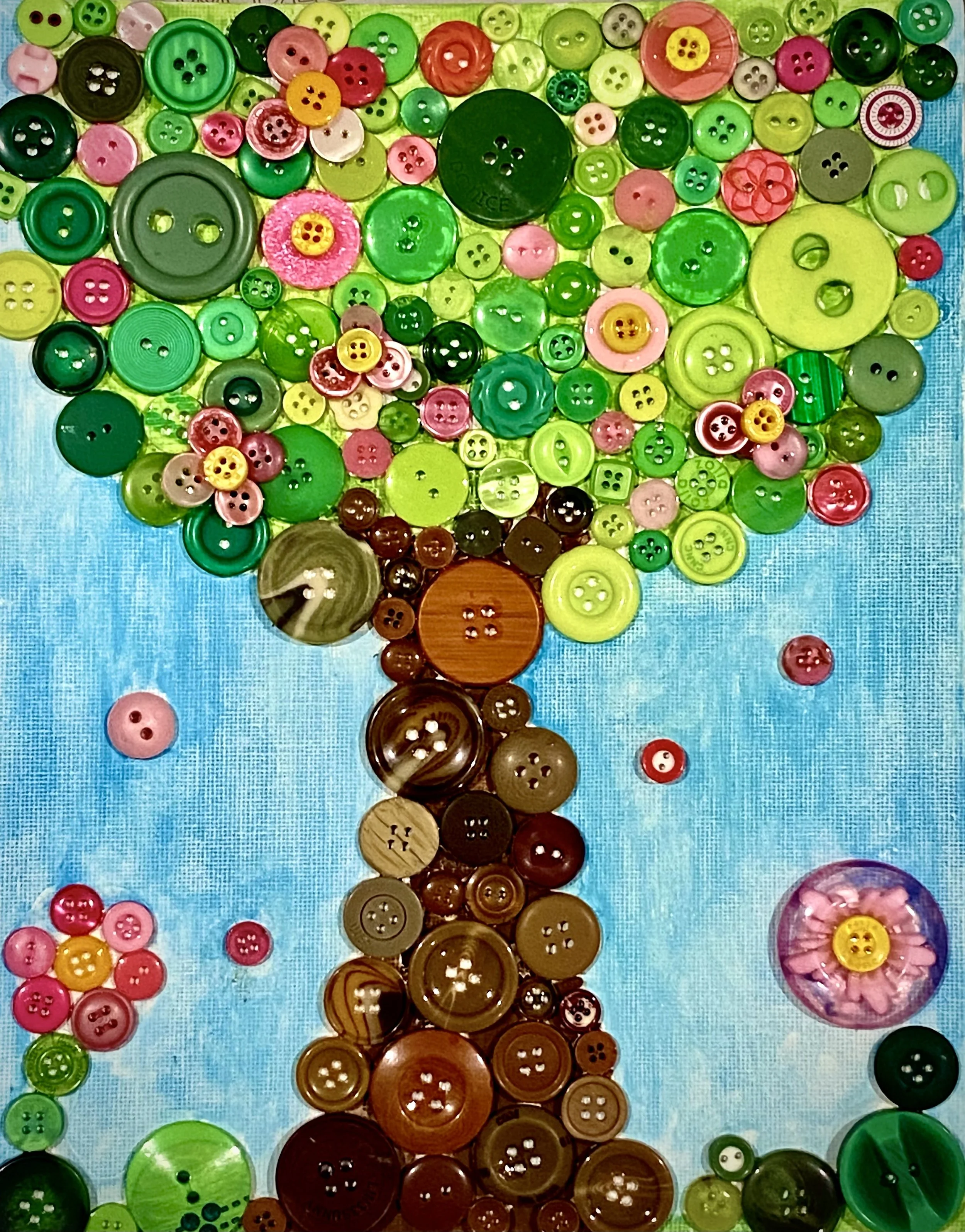 Colorful button artwork arranged in the shape of a tree on a blue background.