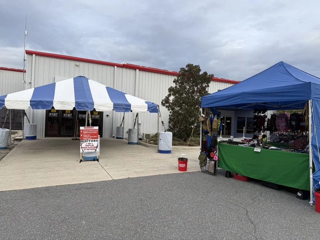 Entrance to the Skylight Hangar with a canopy over the entrance, a sign, and an outdoor exhibit space for gear.