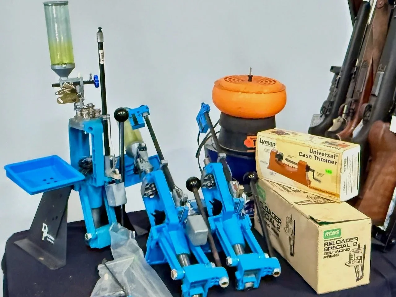 Reloading equipment on a display table. Some parts of rifles are displayed in the background