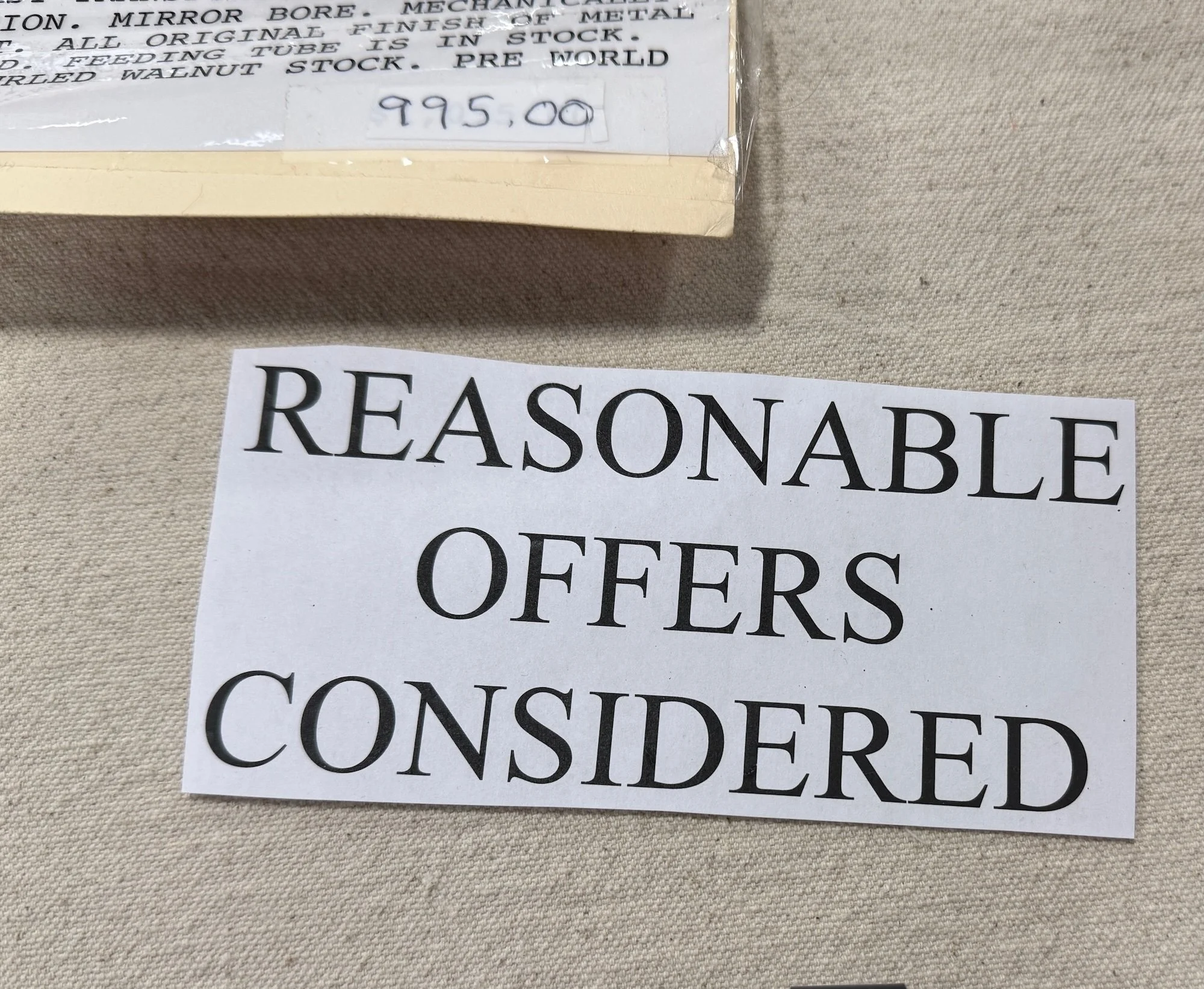Sign with bold text that reads 'Reasonable Offers Considered' on a beige fabric background.