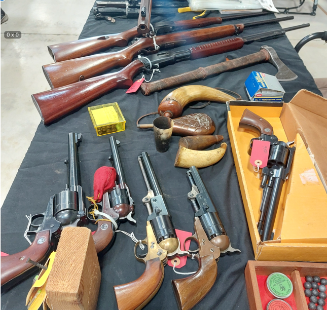 Table display with rifles, ax, pistols.