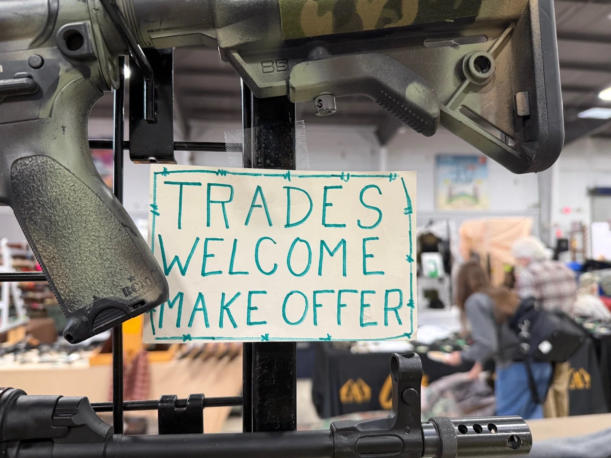 A gun on display at a store with a sign that reads, 'Trades Welcome Make Offer'.