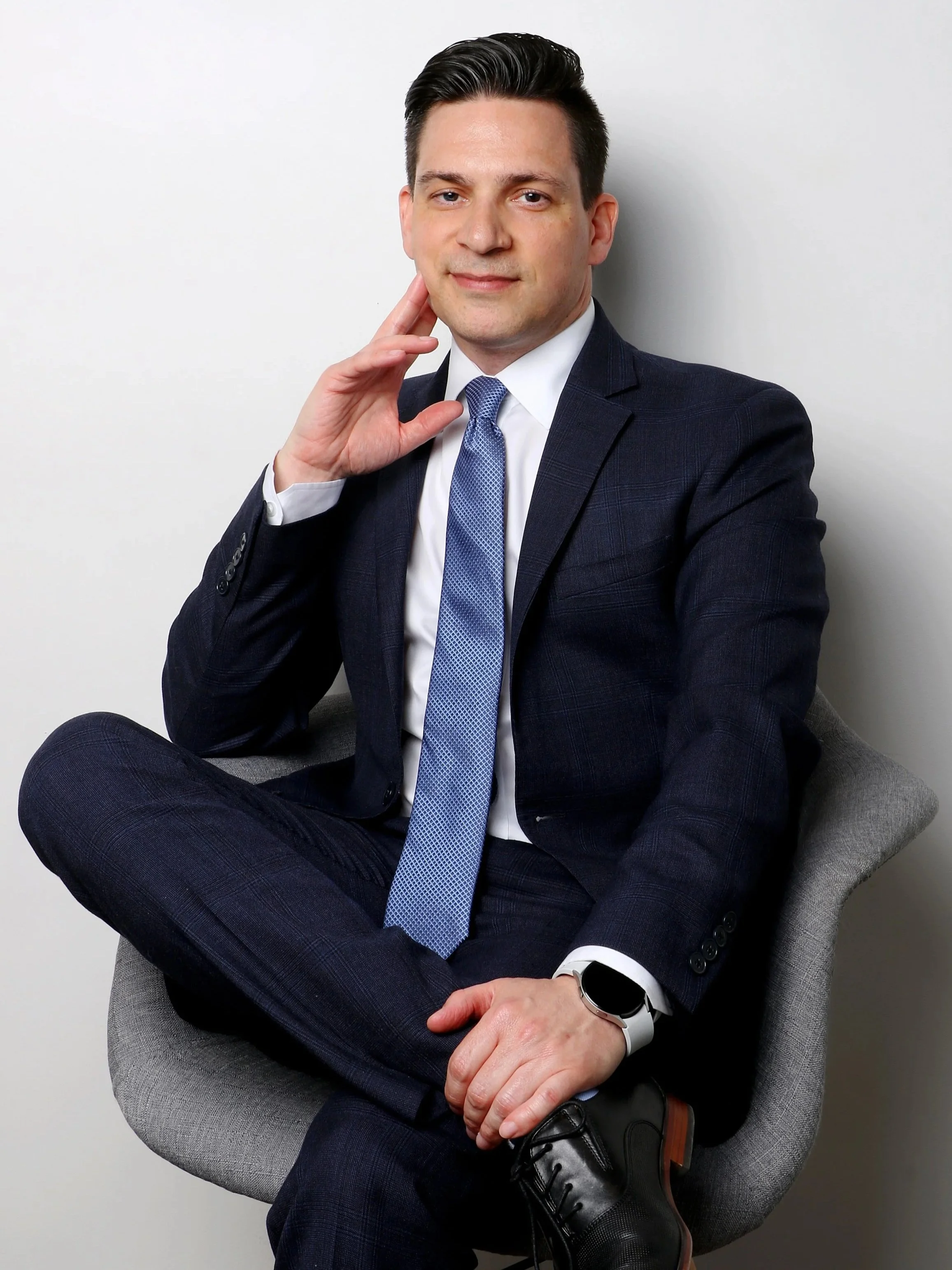 Professionally dressed man in dark navy blue business suit, light blue tie, and black shoes sits confidently with his hand gently touching his cheek beside quote, 'I do not have the sense of hearing, but that does not determine where I can go.'