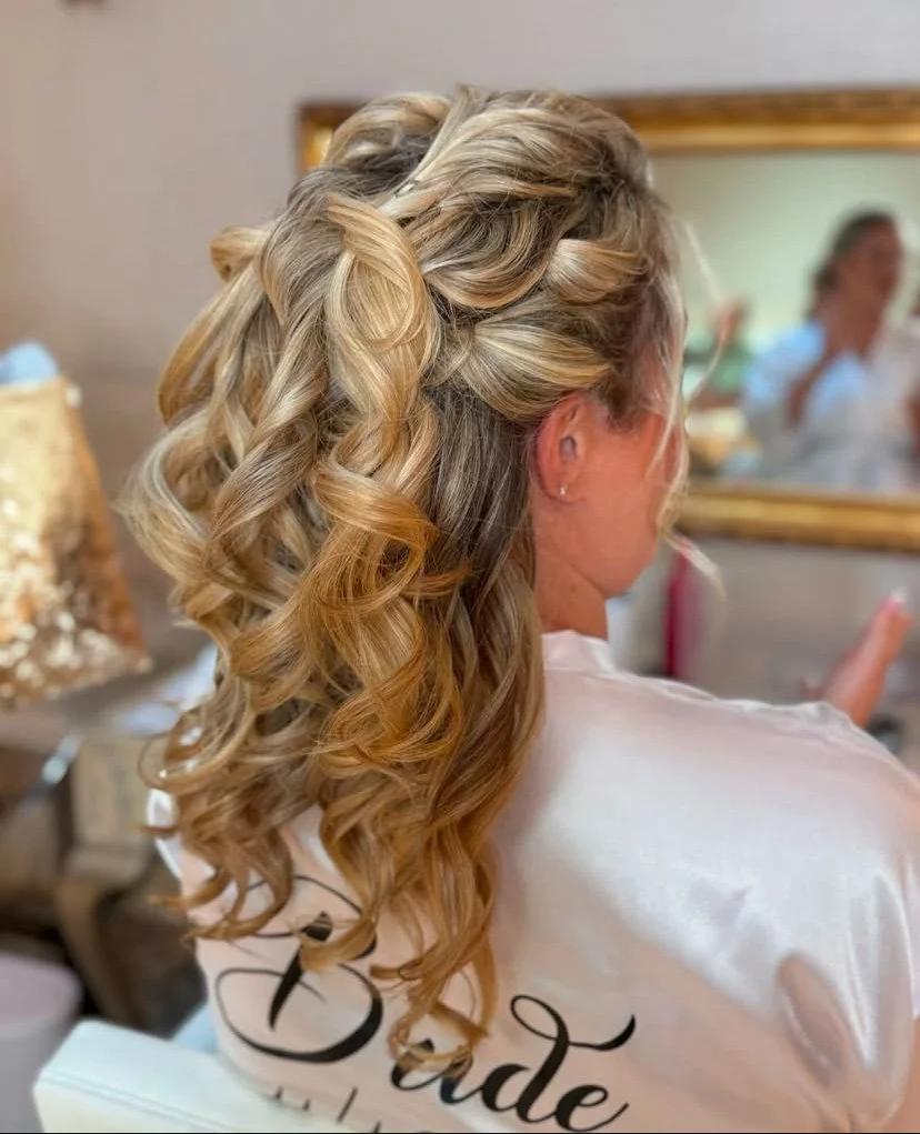 Side view of a bride in her robe with a half-up half-down hairstyle and lose bouncy curls