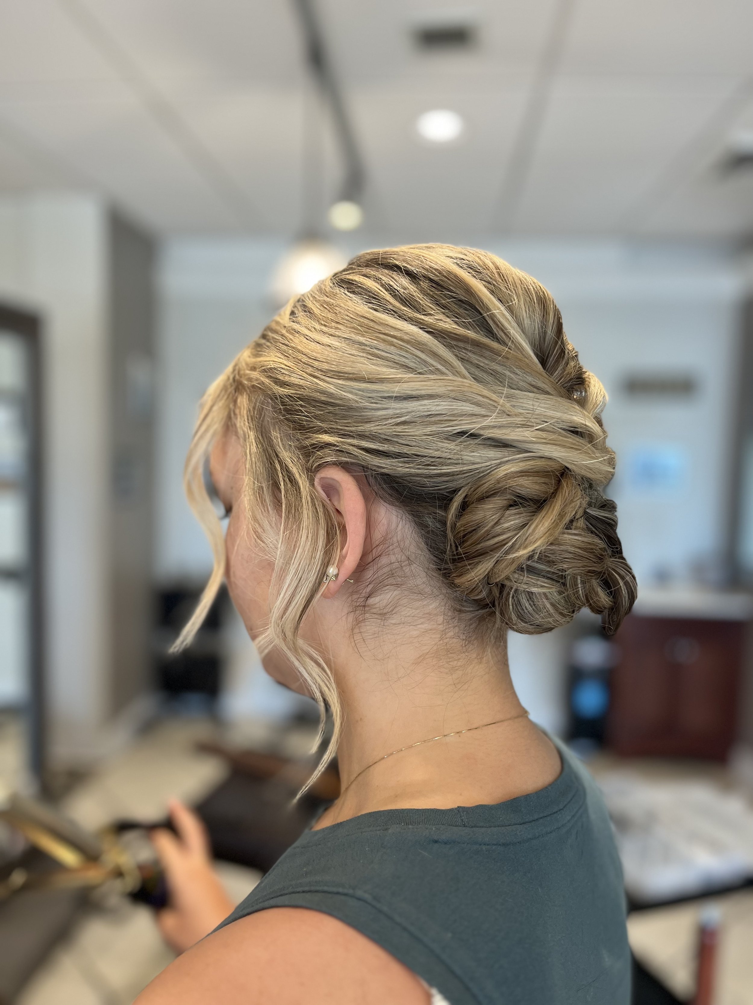 Side view of a bride with a twisted low bun with her front pieces loosely curled.