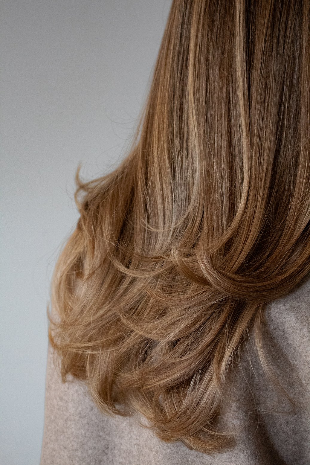 Close-up photo of a client with a blonde blowout by stylist Traci against a white backdrop.