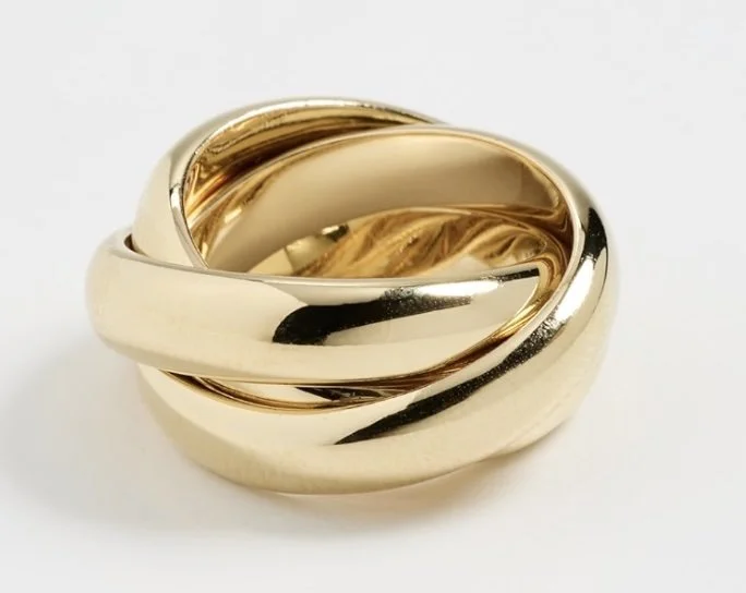 Chunky yellow gold interlocking band statement ring with smooth polished finish, worn as solo jewelry piece