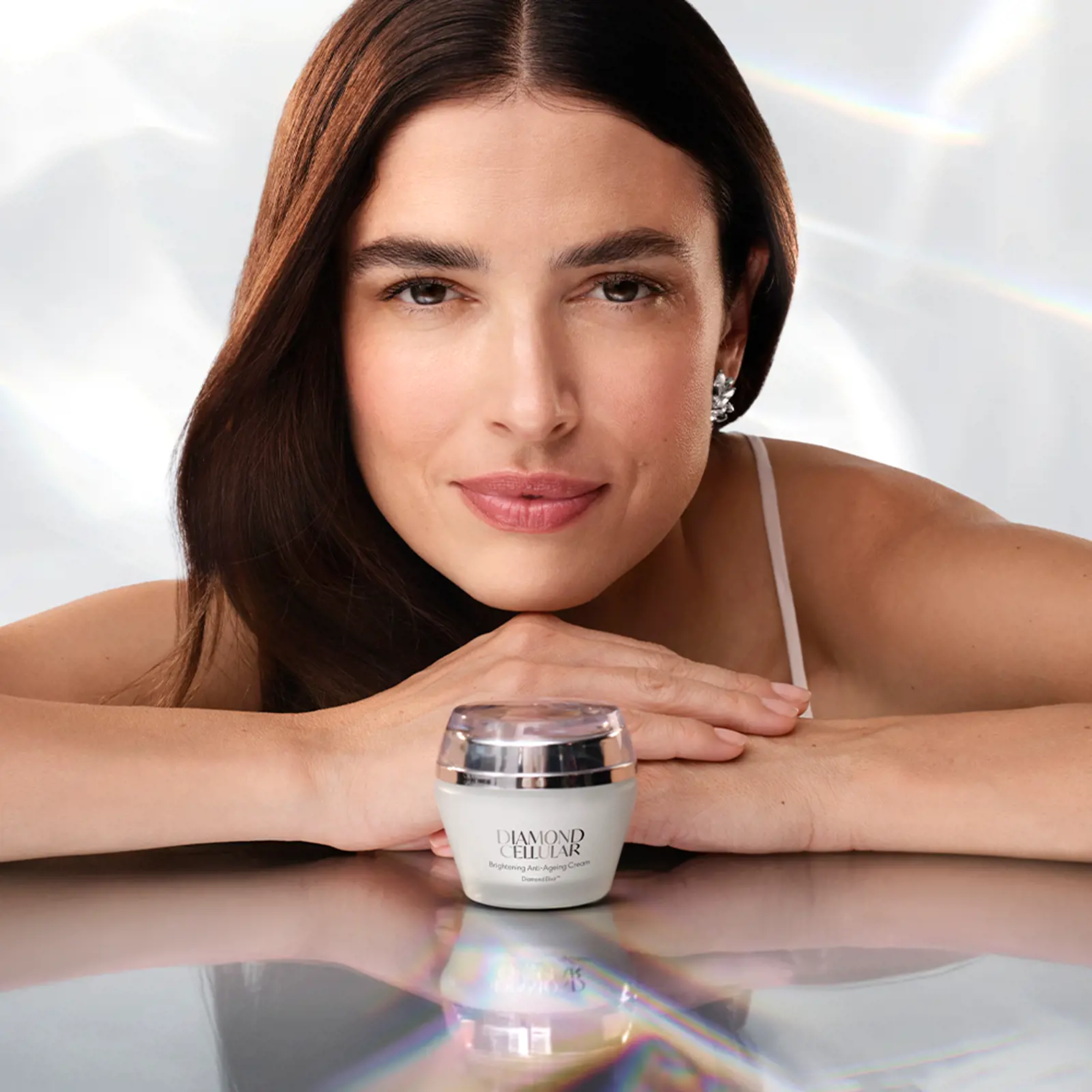 Mujer mostrando un envase de crema Diamond Cellular en primer plano.