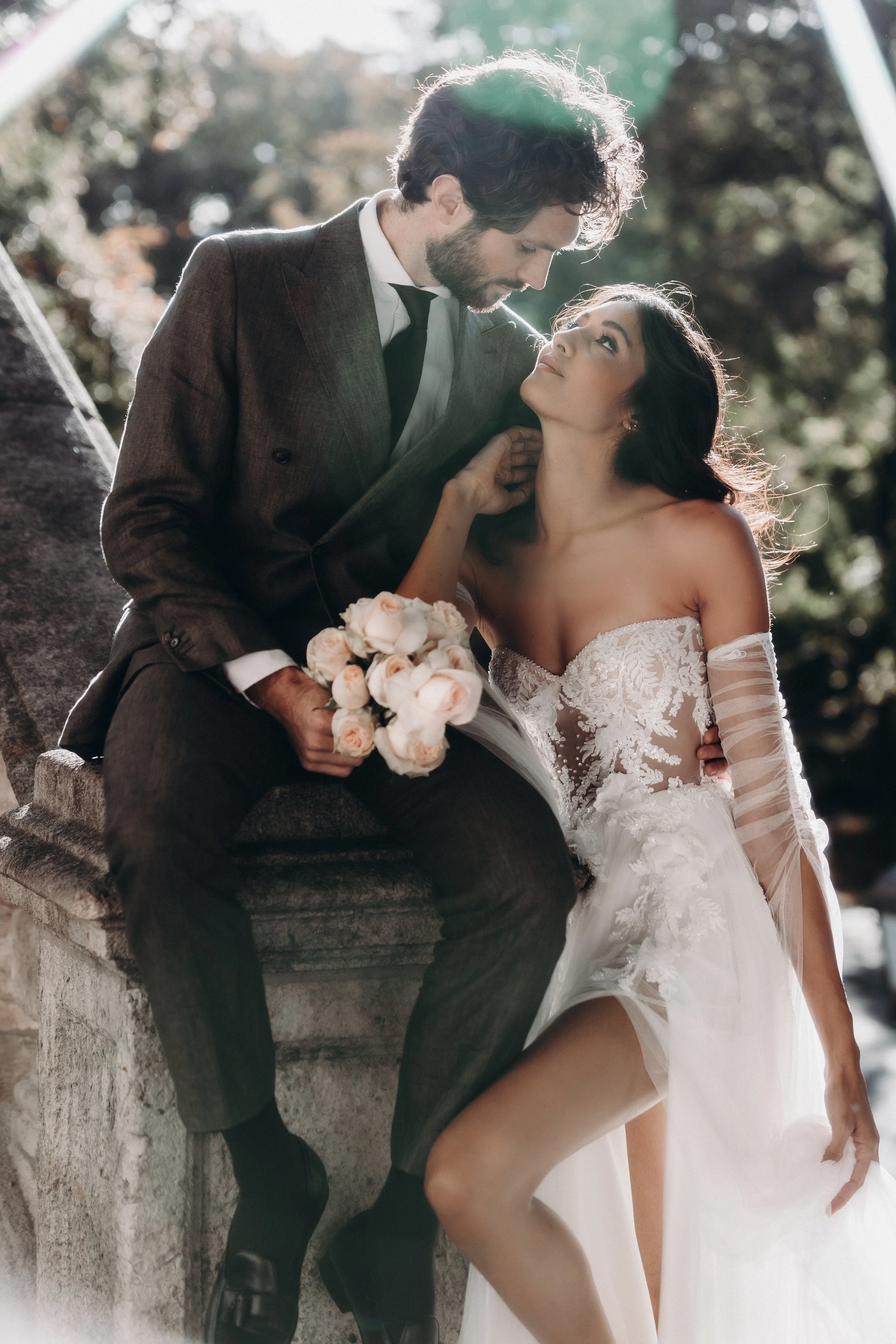 Ein Paar bei einer Hochzeit im Freien, die Frau trägt ein weißes Hochzeitskleid und hält einen Blumenstrauß, der Mann trägt einen dunklen Anzug.