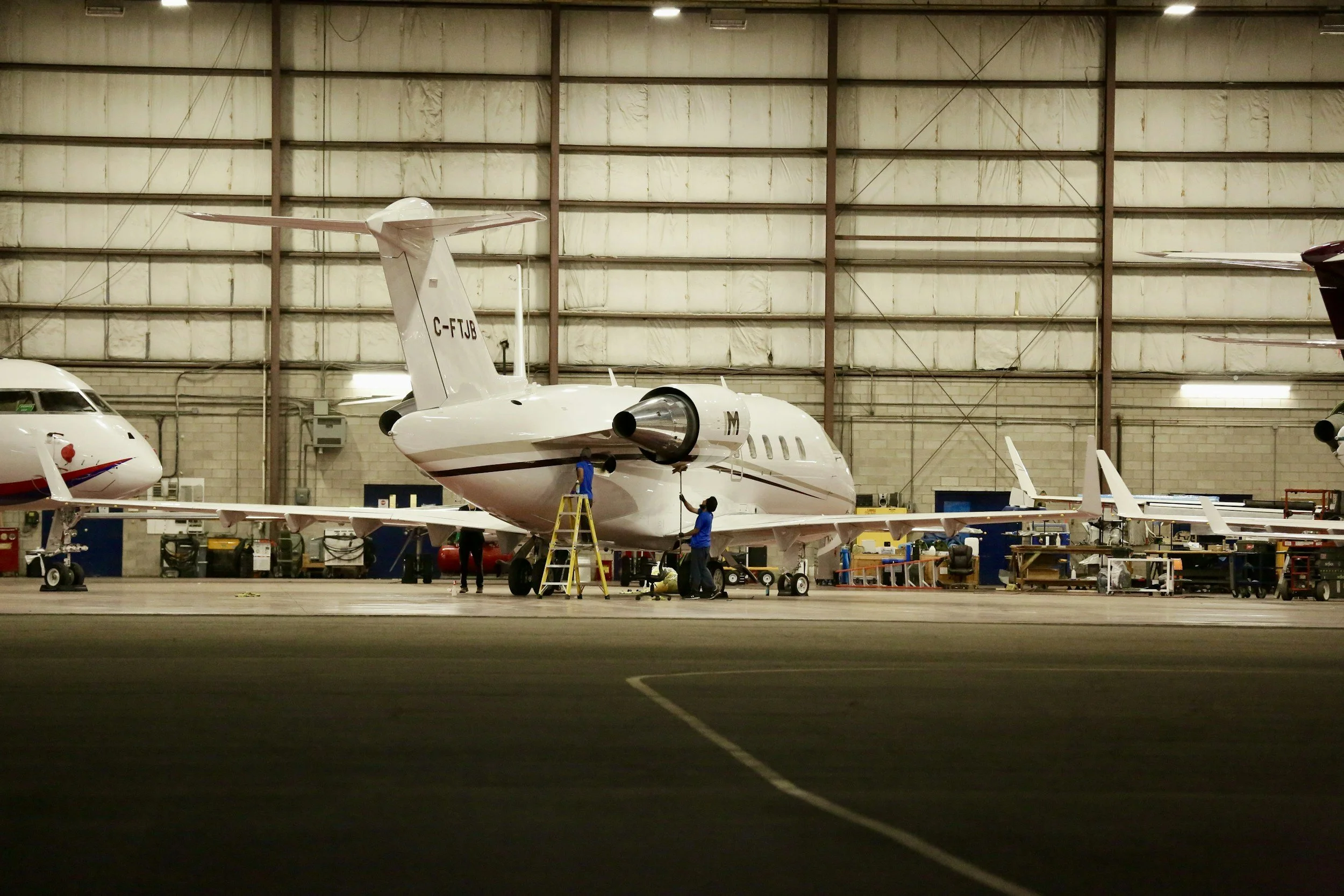 Interior of an airport hangar with a private jet and personnel working on it.
