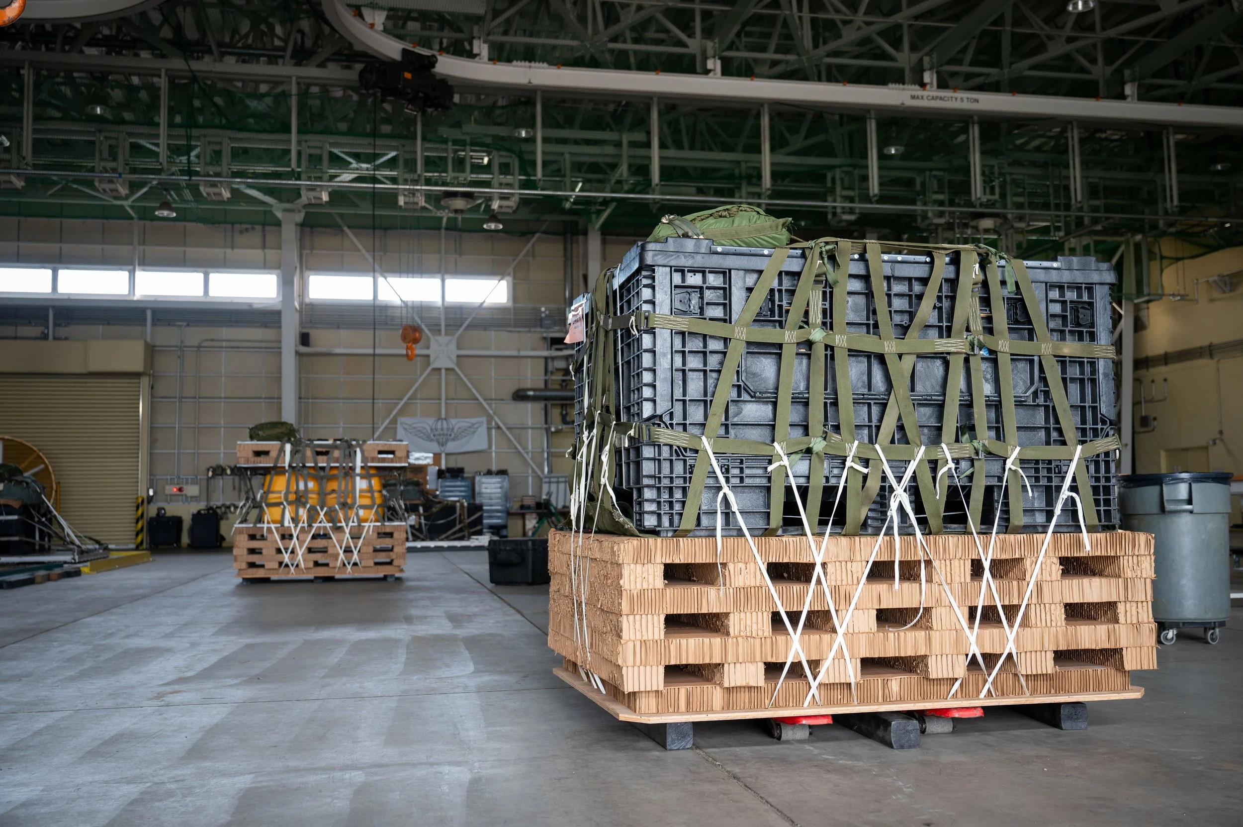 Large crate secured with straps on wooden pallets inside an industrial warehouse.