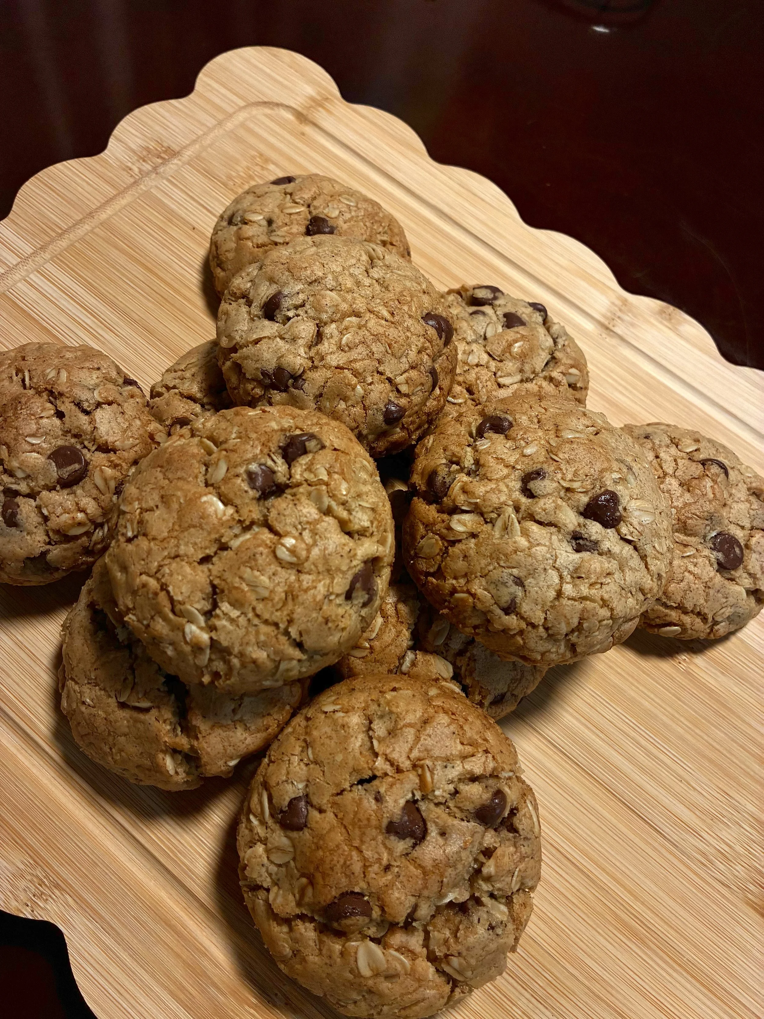 A plate of oatmeal chocolate chip cookies on a wooden serving platter.