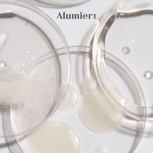 Close-up of clear petri dishes and test tubes containing a white liquid, labeled 'Alumier MD'.