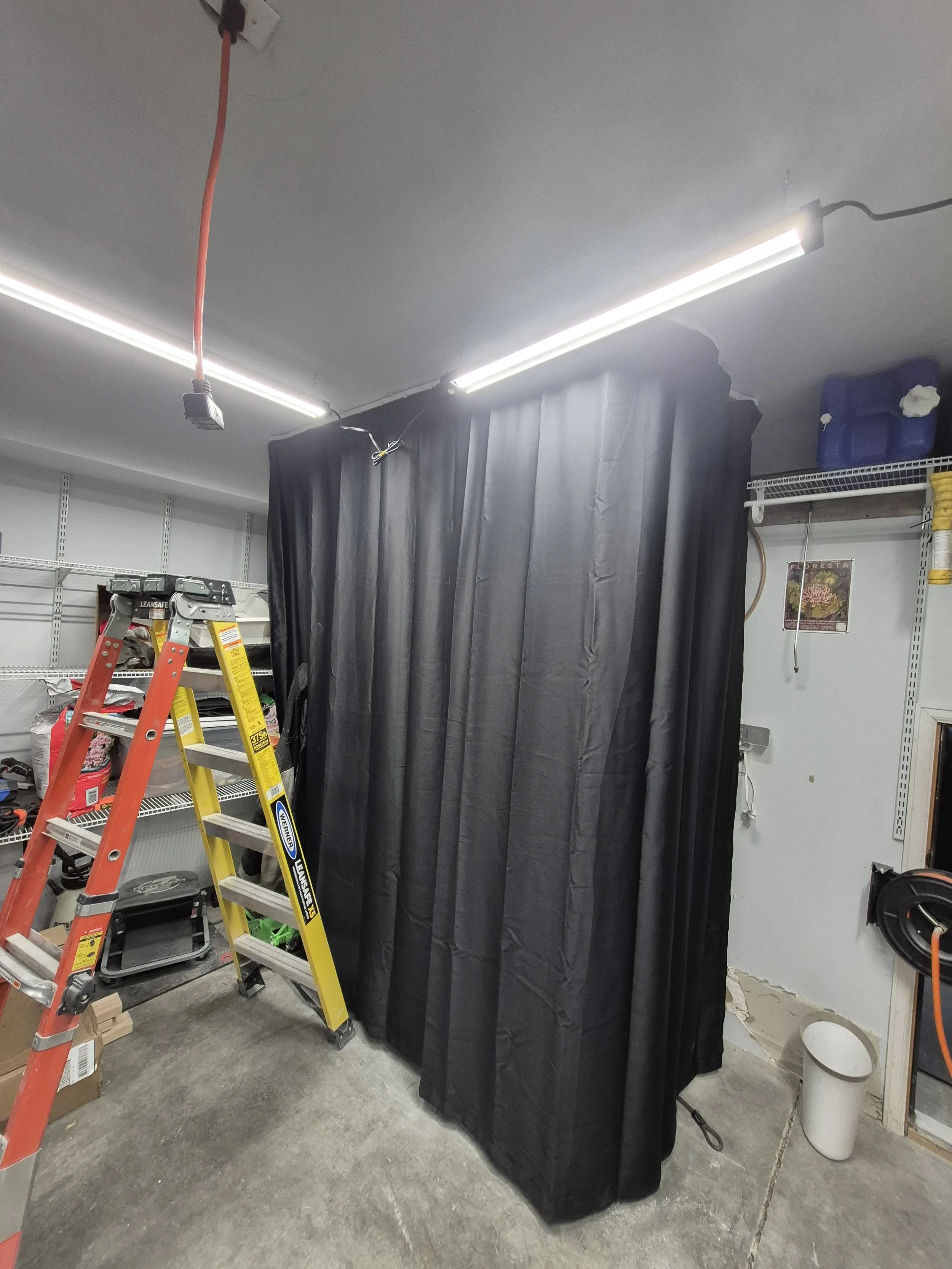 A workshop with black curtains, a ladder, and fluorescent lighting; Thornton, Colorado