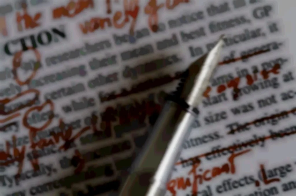 Close-up of a pen writing on a form or document with red and black ink, containing printed and handwritten text.