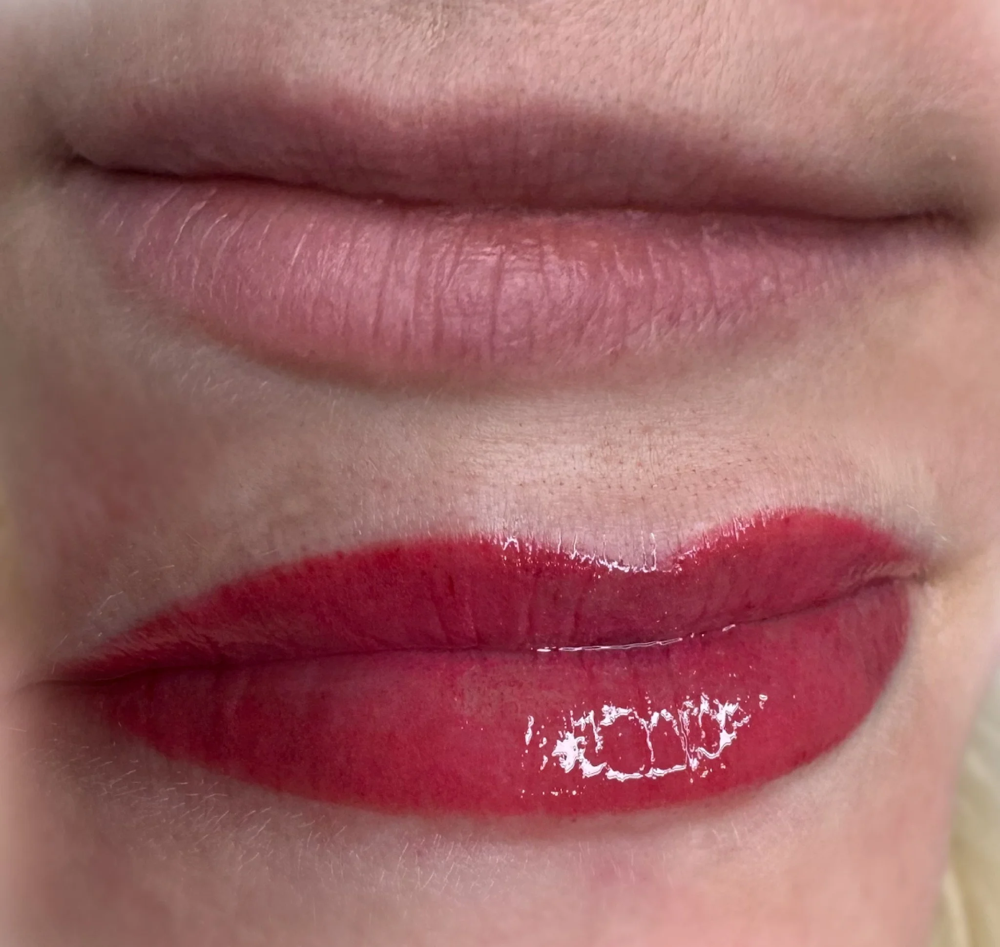 Close-up photo of lips with pink lipstick and smooth skin.