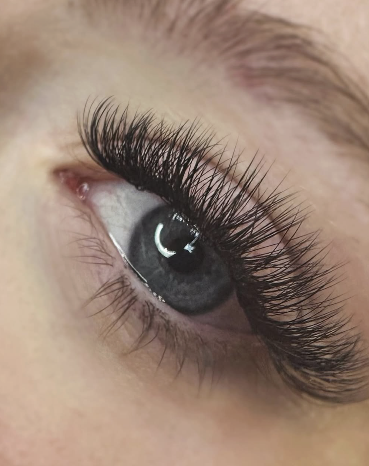 Close-up of a human eye with long, curled eyelashes and a blue iris.