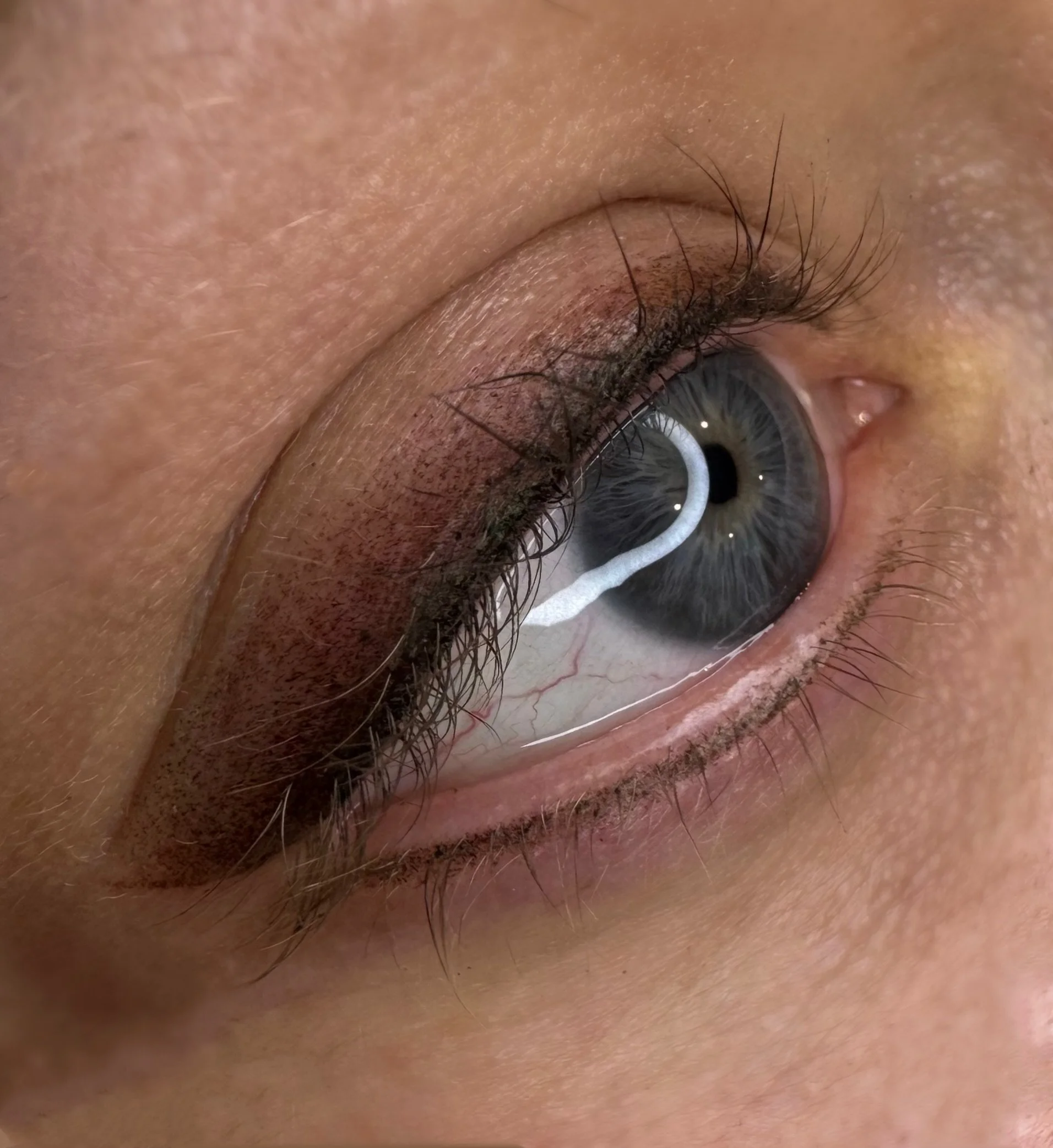 Close-up of a human eye with a reflection of a white light in the cornea.